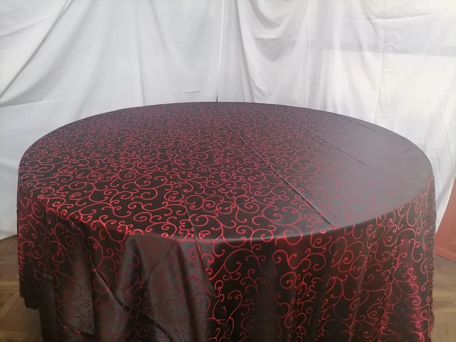 A round table dressed in red and black damask